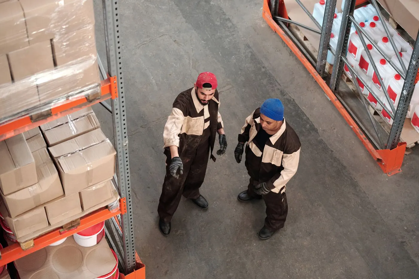 Two people talking through storage in a warehouse aisle